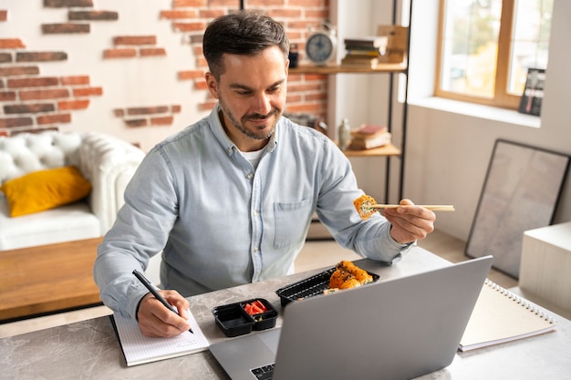 Bezpłatne zdjęcie mężczyzna pod wysokim kątem je sushi i pracuje