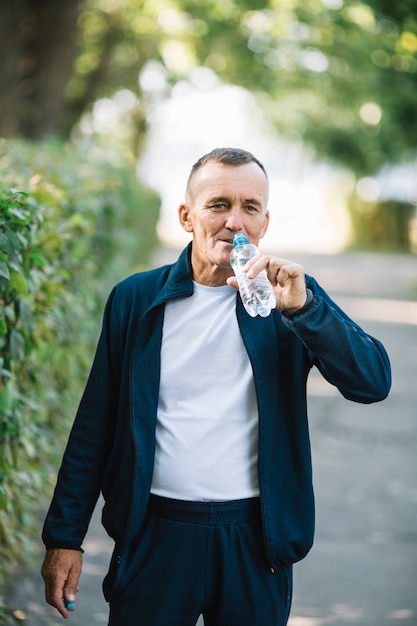 Mężczyzna podnoszenia butelki do buzi do picia wody