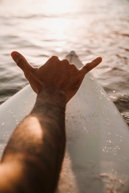 Mężczyzna pokazuje shaka ręki znaka na surfboard