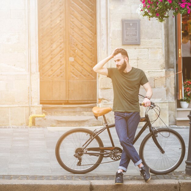 Mężczyzna pozycja z jego bicyklem na chodniczku