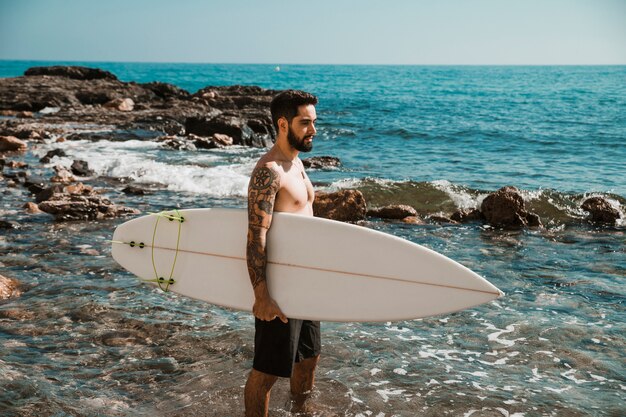 Mężczyzna pozycja z surfboard w błękitne wody