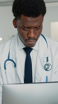 Mężczyzna pracujący jako medyk patrzący na komputer w poszukiwaniu informacji na temat leczenia na oddziale szpitalnym. specjalista medyczny ze stetoskopem i białym fartuchem przy użyciu monitora do leczenia pacjenta