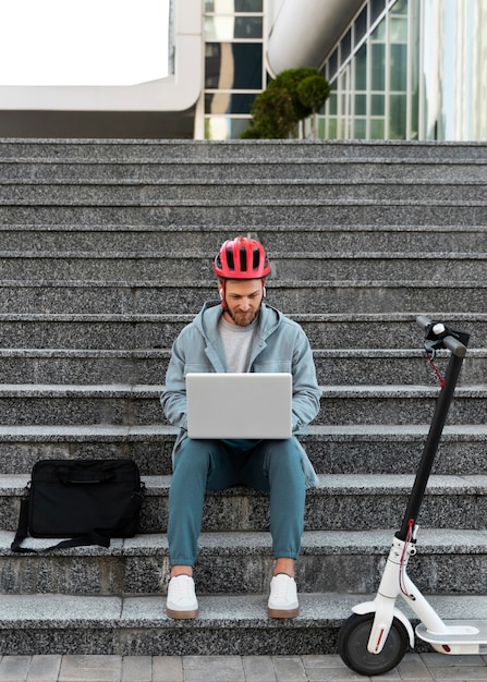 Bezpłatne zdjęcie mężczyzna pracujący na laptopie obok skutera