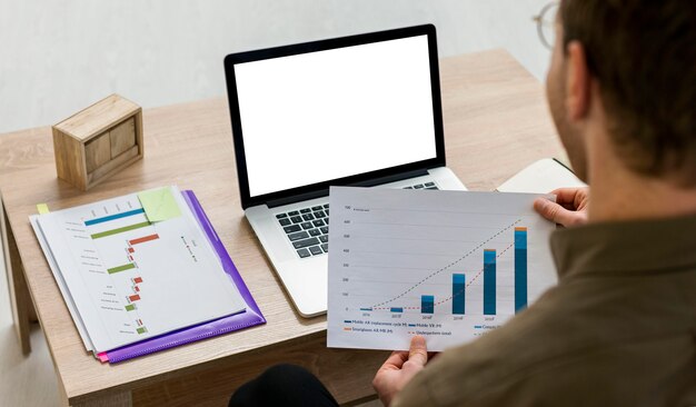 Mężczyzna pracujący na swoim laptopie z infografiki w pomieszczeniu