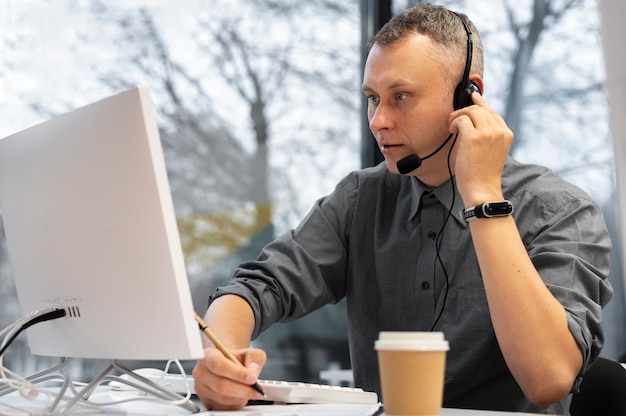 Mężczyzna pracujący w call center ze słuchawkami i komputerem