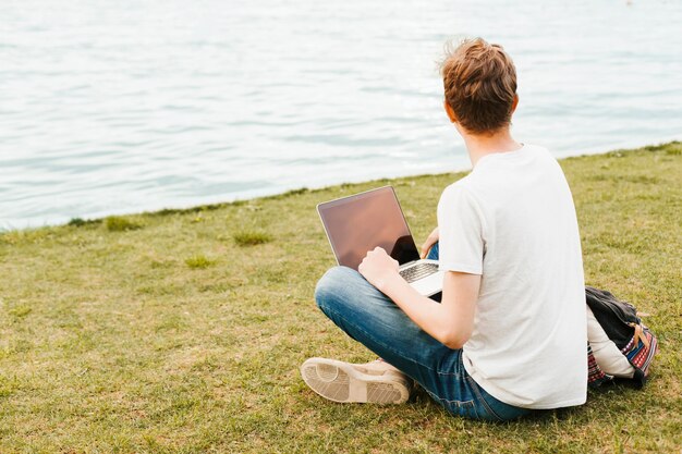 Mężczyzna pracuje na laptopie nad jeziorem