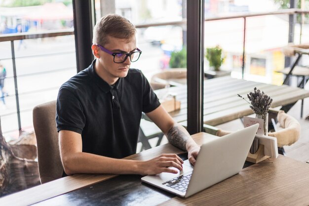 Mężczyzna pracuje na laptopie w kawiarni