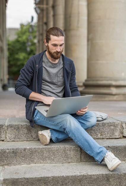 Mężczyzna pracuje na laptopie w mieście