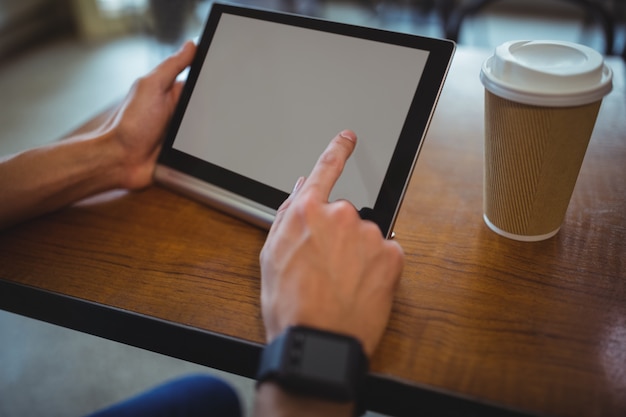 Mężczyzna przy użyciu cyfrowego tabletu w kawiarni