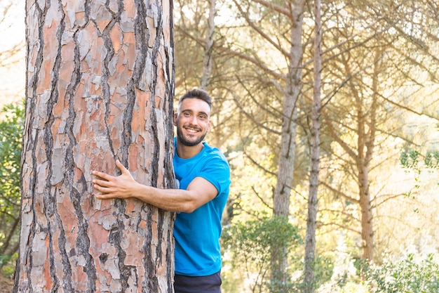 Mężczyzna przytulenia drzewo w uroczym lesie
