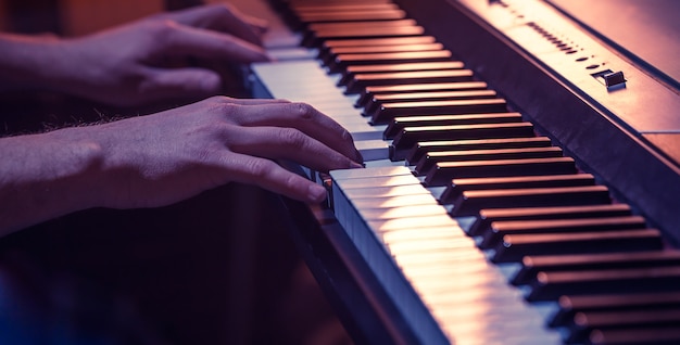 mężczyzna ręce na klawiszach fortepianu zbliżenie piękne kolorowe tło, pojęcie działalności muzycznej