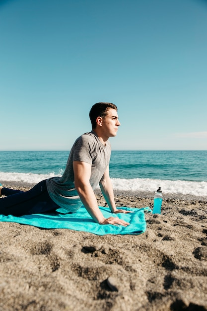 Bezpłatne zdjęcie mężczyzna robi joga przy plażą