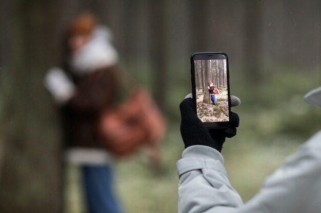 Mężczyzna robi zdjęcia kobiecie podczas zimowej wycieczki po lesie