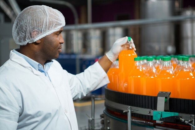 Mężczyzna robotnik sprawdzanie butelek soku w fabryce