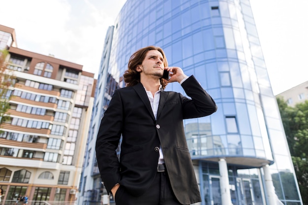 Mężczyzna rozmawia przez telefon przed budynkiem