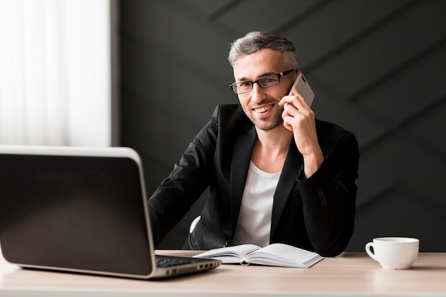 Mężczyzna rozmawia przez telefon z czarną kurtką