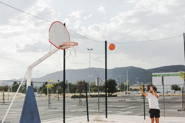 Mężczyzna rzuca koszykówkę w obręczu