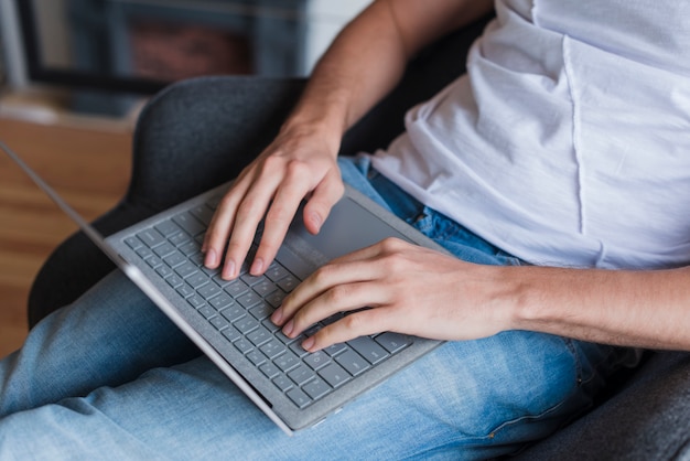 Mężczyzna siedzi na krześle i pisania na laptopa