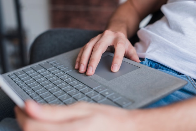 Mężczyzna siedzi na krześle i za pomocą laptopa