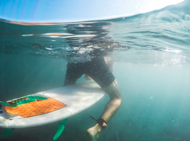 Mężczyzna siedzi na surfboard w błękitne wody w skrótach