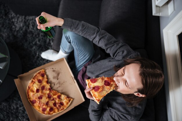 Mężczyzna siedzi w domu w domu jedzenie pizzy