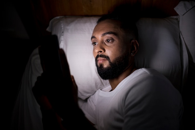 Mężczyzna sprawdza swój telefon przed snem