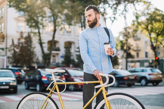 Mężczyzna stoi blisko bicyklu z filiżanką