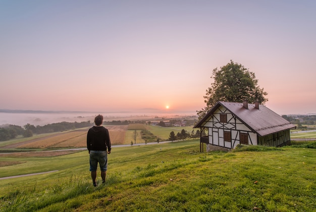 Mężczyzna stoi blisko domu i drzewa przy dniem