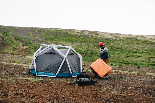 Mężczyzna stoi obok nowoczesnego namiotu w Islandii