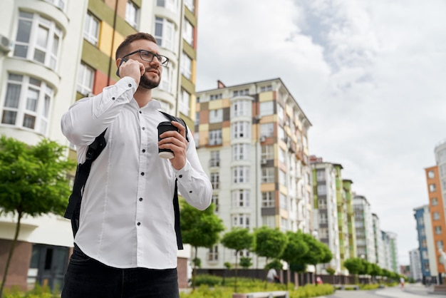 Bezpłatne zdjęcie mężczyzna stojący rozmawiający przez telefon i patrzący na nowe budynki