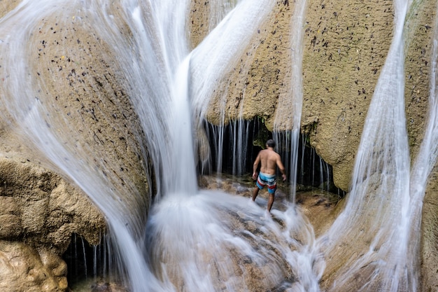 Bezpłatne zdjęcie mężczyzna stojący w szortach w jaskini, w której za dnia leje woda