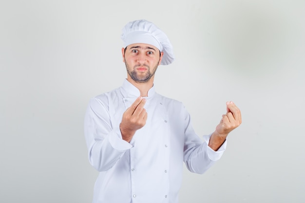 Mężczyzna szefa kuchni pokazując gest rękami w białym mundurze i wyglądający na zdezorientowanego