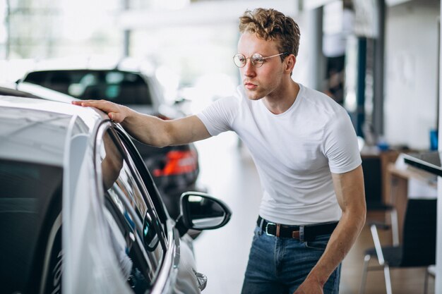 Mężczyzna szuka samochodu w salonie samochodowym