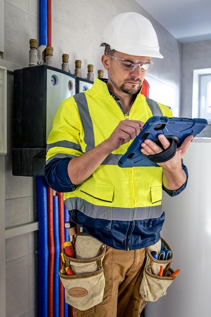 Bezpłatne zdjęcie mężczyzna, technik elektryk pracujący w rozdzielnicy z bezpiecznikami, korzysta z tabletu