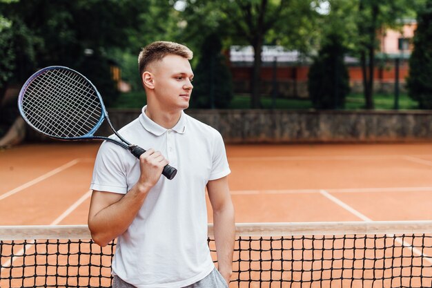 Mężczyzna tenisista na sądzie patrząc szczęśliwy trzymając rakietę.