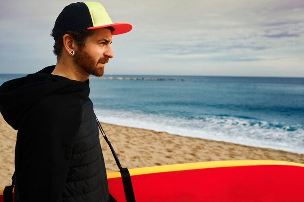 Mężczyzna trzyma deskę surfingową na plaży