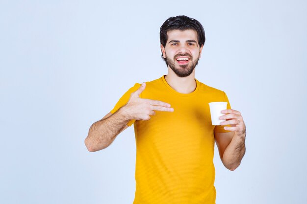 Mężczyzna trzyma i promuje filiżankę kawy.