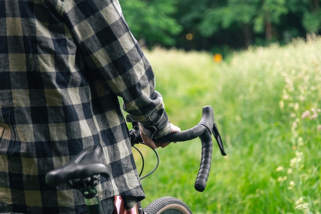 Bezpłatne zdjęcie mężczyzna trzyma kierownicę roweru i spaceruje po lesie