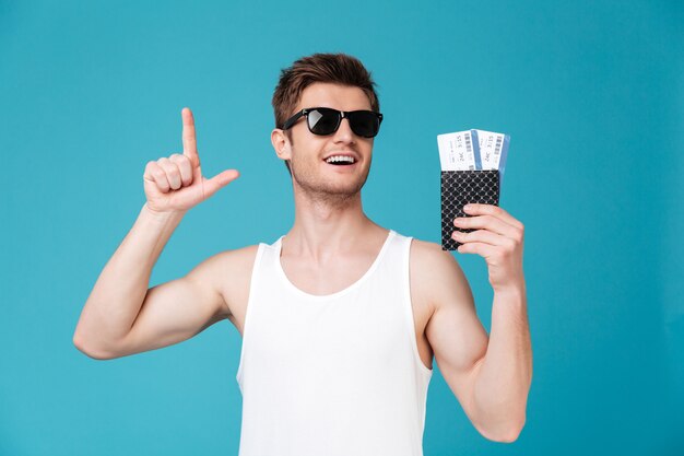 Mężczyzna trzyma paszport z biletami w okularach przeciwsłonecznych