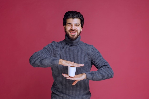 Bezpłatne zdjęcie mężczyzna trzyma w ręku jednorazową filiżankę kawy i czuje się pozytywnie.