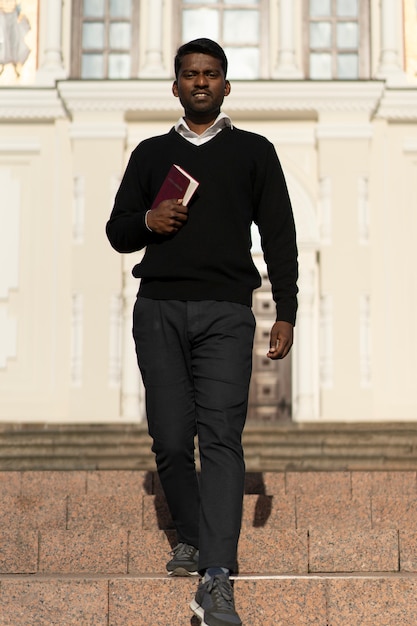 Bezpłatne zdjęcie mężczyzna trzymający książkę biblijną przed kościołem