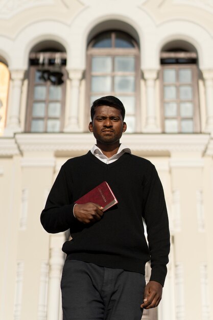 Mężczyzna trzymający książkę biblijną przed kościołem
