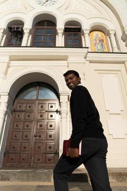 Mężczyzna trzymający książkę biblijną przed kościołem