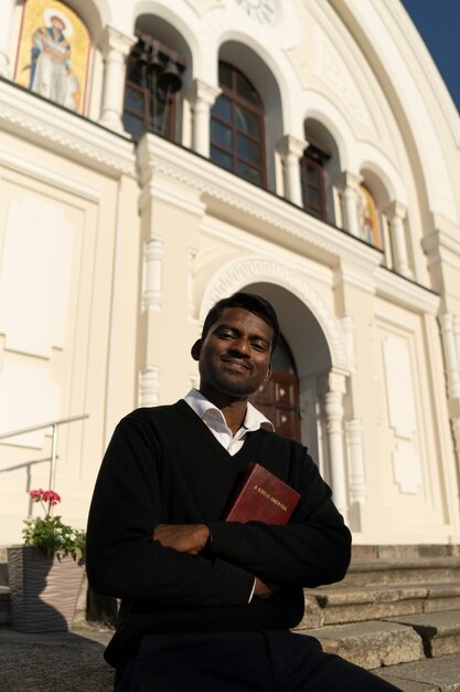 Mężczyzna trzymający książkę biblijną przed kościołem