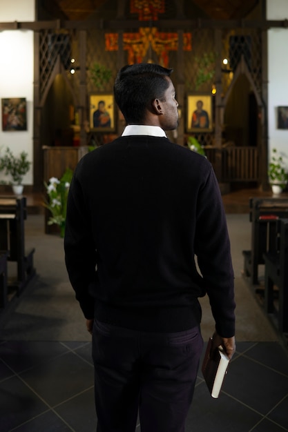 Bezpłatne zdjęcie mężczyzna trzymający księgę biblijną w kościele