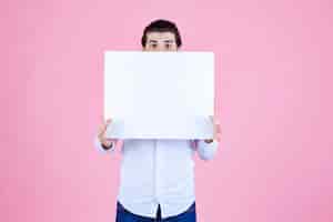Bezpłatne zdjęcie mężczyzna trzymający przed sobą pustą kwadratową tablicę.