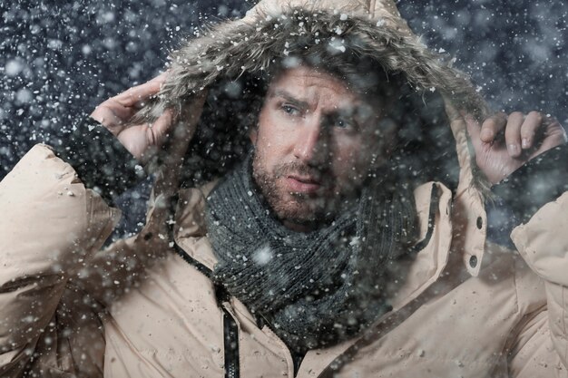 mężczyzna ubrany w kurtkę zimową, gdy pada śnieg