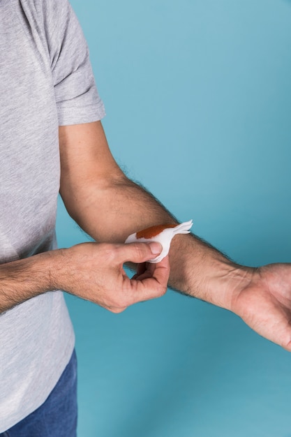 Bezpłatne zdjęcie mężczyzna usuwa biały medyczny bandaż na krwawiącym nadgarstku