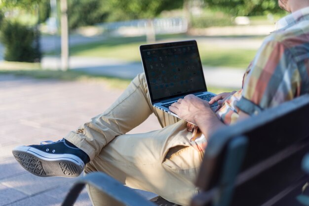 Mężczyzna używa laptop w parku