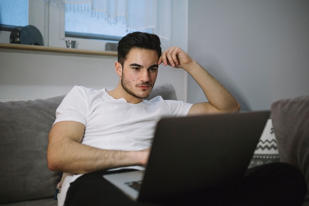 Mężczyzna używa laptop w żywym pokoju